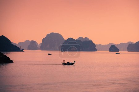 Téléchargez les photos : Petits bateaux au milieu des formations karstiques en mer. Îles dans la célèbre baie de Ha Long au Vietnam - en image libre de droit
