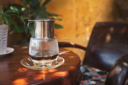 Téléchargez les photos : Verre de café vietnamien chaud traditionnel avec du lait condensé sur une table en bois dans un café au Vietnam - en image libre de droit