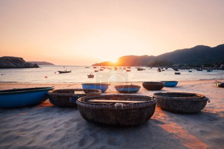 Photo for Basket boats on sand beach in bay against sea at beautiful sunset. Fishing village on Cham Islands in Vietnam - Royalty Free Image