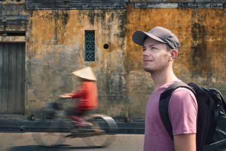 Foto de Retrato de viajero con mochila. Hombre explorando calles de la antigua ciudad Hoi An en Vietnam - Imagen libre de derechos