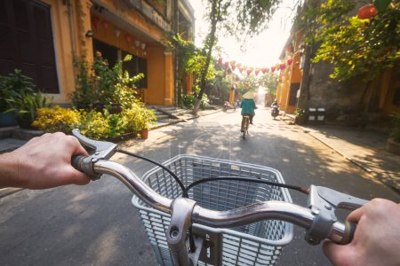 Foto de POV montar en bicicleta de turista en la antigua ciudad de Hoi An en Vietnam. Enfoque selectivo en el manillar de mano - Imagen libre de derechos