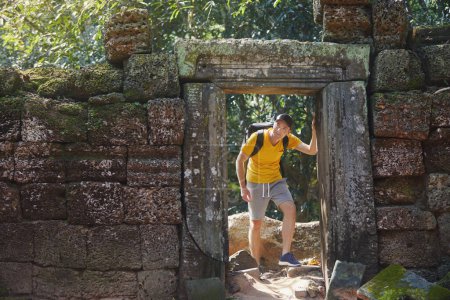 Photo for Man walking through old ruins and coming to mysterious ancient temple in the middle of jungle. Traveler in Cambodia - Royalty Free Image
