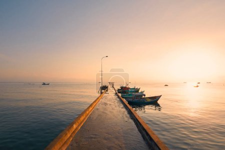 Foto de Salida del sol sobre el horizonte del mar. Muelle largo con botes amarrados en pueblo pesquero en la isla de Phu Quoc, Vietna - Imagen libre de derechos
