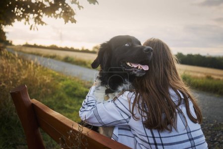 Photo for Happy teen girl hugging her dog on wooden bench. Joyful Czech Mountain Dog with pet owner - Royalty Free Image