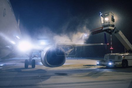 Enteisung des Flugzeugflügels vor dem Flug. Winterfrostige Nacht und Bodendienst am Flughafen bei Schneefall