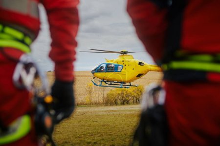 Photo for Rear view of paramedics as they looking at landing helicopter of emergency medical service. Themes rescue, urgency and health care. - Royalty Free Image