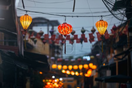 Téléchargez les photos : Lanternes traditionnelles suspendues sur la vieille rue de Hoi An au Vietnam. Vie nocturne dans la ville antique - en image libre de droit