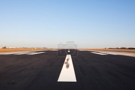 Photo for Surface level of long airport runway with directional marking against clear sky. - Royalty Free Image