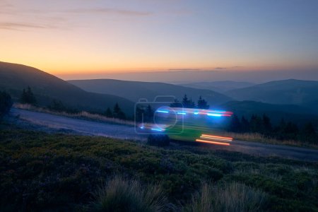 Téléchargez les photos : Sentiers lumineux de voiture ambulance du service médical d'urgence sur la route de montagne la nuit. Thèmes santé, secours et urgence - en image libre de droit