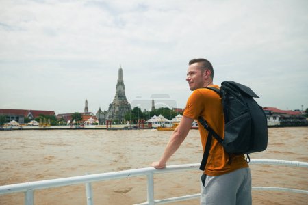 Téléchargez les photos : Voyageur avec sac à dos est profiter de la vue du ferry-boat au temple Wat Arun à Bangkok. Belle destination de voyage en Thaïlande. - en image libre de droit