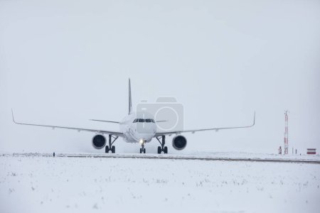 Foto de Tráfico en el aeropuerto durante las nevadas. Avión de pasajeros viajando a la pista para despegar en el helado día de invierno - Imagen libre de derechos