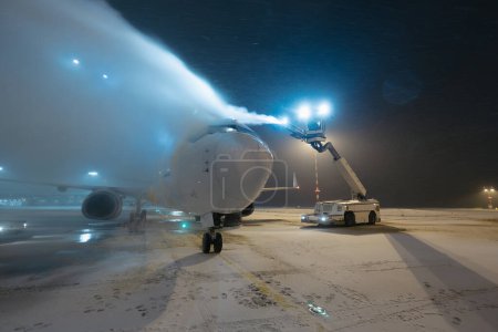 Foto de Deshielo del avión antes del vuelo. Invierno noche helada y servicio terrestre en el aeropuerto durante las nevadas - Imagen libre de derechos