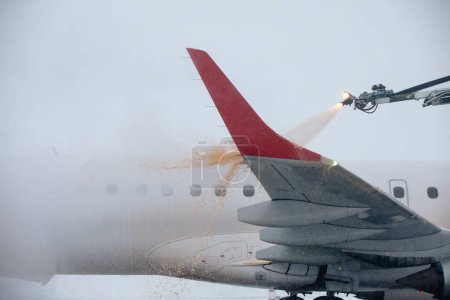 Foto de Deshielo del ala del avión antes del vuelo. Invierno helado día y servicio terrestre en el aeropuerto durante las nevadas - Imagen libre de derechos