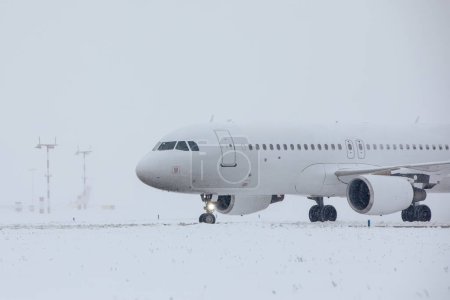 Foto de Tráfico en el aeropuerto durante las nevadas. Avión de pasajeros viajando a la pista para despegar en el helado día de invierno - Imagen libre de derechos