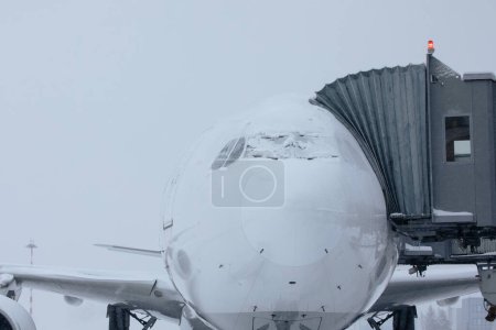 Foto de Aeropuerto cerrado durante las fuertes nevadas. Avión cubierto de nieve durante el frío día de invierno. Contexto de clima extremo en el transporte con espacio para copias. - Imagen libre de derechos