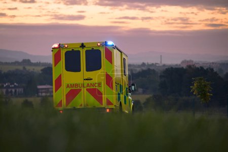 Téléchargez les photos : Voiture d'ambulance jaune du service médical d'urgence sur la route de campagne. Thèmes sauvetage, urgence et soins de santé. - en image libre de droit