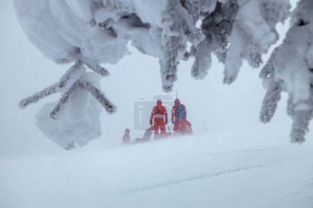 Téléchargez les photos : Équipe paramédicale des services d'urgence aidant dans les montagnes en hiver pendant le blizzard. Thèmes sauvetage dans des conditions météorologiques extrêmes - en image libre de droit