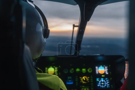 Photo for Pilot of helicopter emergency medical service flying over landscape at dusk. Themes emergency medicine, rescue, and emergency help - Royalty Free Image