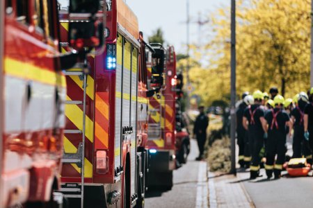 Photo for Red fire trucks in row. Teams of fire brigade on city street. Selective focus on blue flasher. - Royalty Free Image