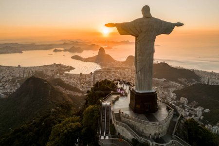 Foto de Río de Janeiro, Brasil - 21 de marzo de 2023: Estatua de Cristo Redentor en la cima de la montaña del Corcovado con el Pan de Azúcar en el horizonte al amanecer. - Imagen libre de derechos