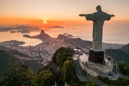 Photo for Rio de Janeiro, Brazil - March 21, 2023: Christ the Redeemer statue on top of the Corcovado Mountain with the Sugarloaf Mountain in the  horizon on sunrise. - Royalty Free Image