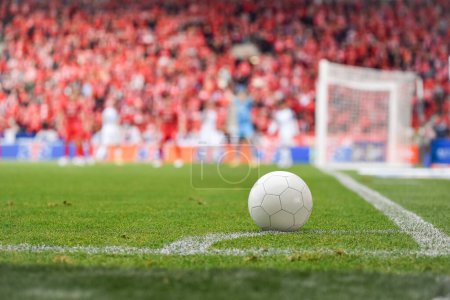 Photo for White ball at the corner of soccer pitch with players and fans in background. - Royalty Free Image