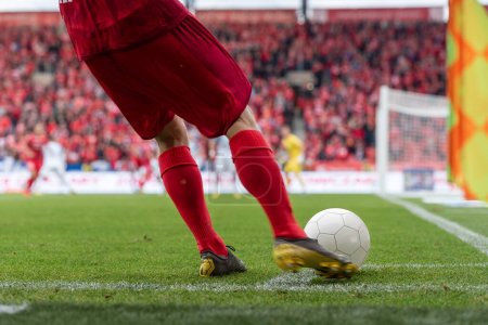 Foto de El futbolista toma la esquina. Detalle de las piernas del jugador y la pelota durante el partido de fútbol. - Imagen libre de derechos