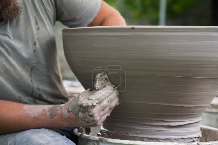 Photo for Hands of a man making a clay vase on a potter's wheel - Royalty Free Image