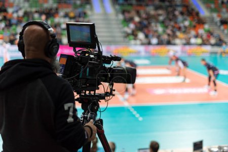 Professional TV camera with volleyball match in the background.