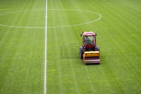 Photo for A man in a tractor with a disc seeder drill sowng grass at the football field - Royalty Free Image