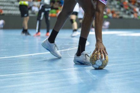 Photo for Handball woman player raises ball from parquet during the match. - Royalty Free Image