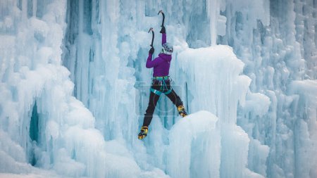 Foto de Mujer alpinista con equipo de escalada en hielo en una cascada congelada - Imagen libre de derechos
