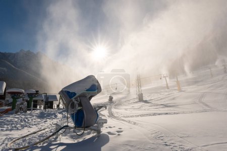 Schneekanonen oder Schneeerzeuger in Aktion an einem kalten, sonnigen Wintertag im Skigebiet Kranjska Gora, Slowenien