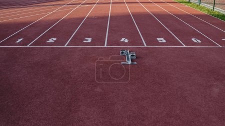 Foto de Bloqueo de salida y línea de salida de la pista atlética de tartán rojo con ocho carriles, tiro con dron. - Imagen libre de derechos