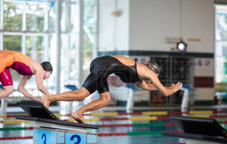 Téléchargez les photos : Deux nageuses professionnelles en position de départ de piste sur la plate-forme sautent gracieusement et plongent dans une piscine. Concept de compétition sportive. - en image libre de droit