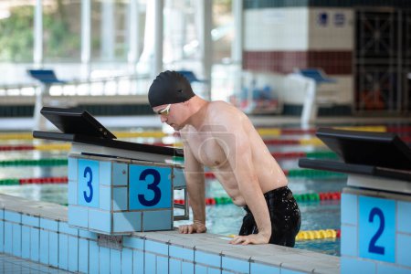Photo for Fit strong swimmer with a black swimming cap looking at the pool with swimming goggles. - Royalty Free Image