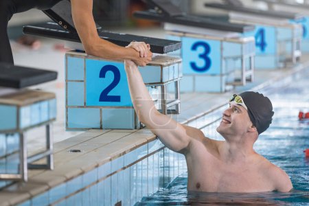 Photo for Swimming teammates giving high five in the pool at the finish of a race - Royalty Free Image