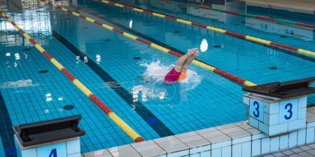Photo for Female athlete, a professional swimmer during training, preparing for a dive start and jumping into the lap pool. - Royalty Free Image