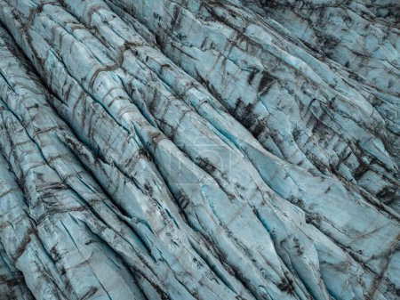 Ice terraces of glacier tongue, rough surface with crack pattern dirty white color, aerial directly above view. Nature, background and design concepts.