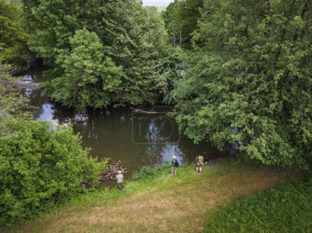 Three Fishermens fishing on the river band surrounded by beautiful nature in the summer season, aerial shot. Outdoor lifestyle, relax, and unwind concepts.