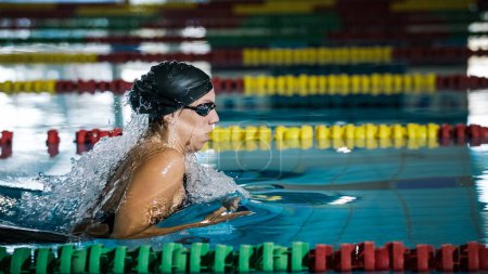 Powerful and persistent professional female swimmer swimming breaststroke at speed. Endurance, effort, and focus concept.