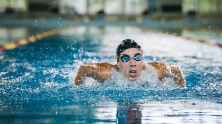 Vista frontal de una nadadora estilo mariposa nadadora, un derrame cerebral que actúa en una natación competitiva. Concepto de éxito, poder y fuerza.