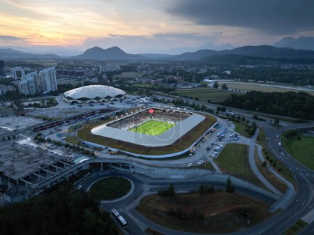 Modern complex of sport park in Ljubljana, Slovenia capital city, and its picturesque mountain setting at sunset, aerial view.