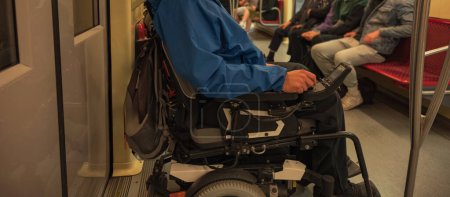 Mann mit Behinderung mit Elektro-Rollstuhl im Zug Inklusives und barrierefreies Nahverkehrskonzept.