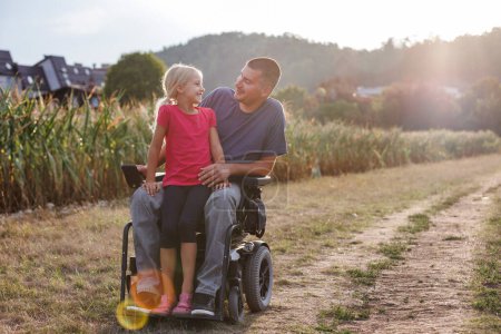 Moment of happiness, a little girl and her father a wheelchair user enjoying together time in nature. Disability and family concept.