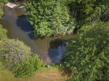 Two Fishermens fishing on the river band surrounded by beautiful nature in the summer season, aerial shot. Outdoor lifestyle, relax, and unwind concepts.