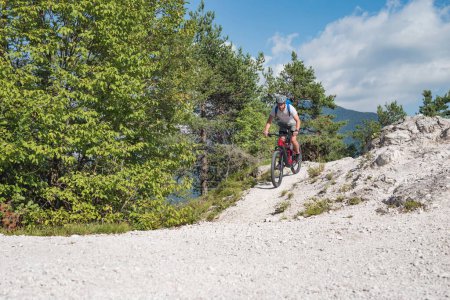Recreational cyclist riding an electric mountain bike on white gravel path. EMTB cycling concept.