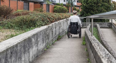 Körperbehinderte Personen, die mit einem Rollstuhl über eine barrierefreie Rampe auf die Straße gelangen. Konzepte für Behinderungen und Mobilität.