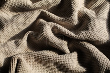 Beige waffle weave cotton fabric with light and shadow. Closeup of light natural cotton texture pattern for background.