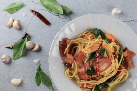 Espaguetis Bacon ají albahaca al ají en plato blanco sobre fondo gris. Menú popular plato de cocina italiana clásica. Deliciosa comida picante.